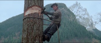 Movie still from “The Journey of Natty Gann” (1985), directed by Jeremy Kagan – A man is cutting a tree with an axe; Medium shot, Low angle