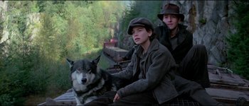Movie still from “The Journey of Natty Gann” (1985), directed by Jeremy Kagan – Two young men sitting next to a dog on a train track; Medium shot, High angle