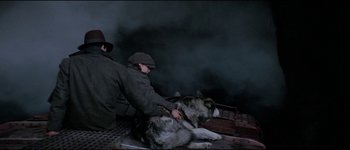 Movie still from “The Journey of Natty Gann” (1985), directed by Jeremy Kagan – A man and a dog are sitting on a dock; Medium shot, Overhead angle