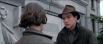 Movie still from “The Journey of Natty Gann” (1985), directed by Jeremy Kagan – A man wearing a brown hat talking to another man; Close Up shot, Over the shoulder angle