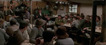Movie still from “The Journey of Natty Gann” (1985), directed by Jeremy Kagan – A group of men sitting around a table; Wide shot, Over the shoulder angle