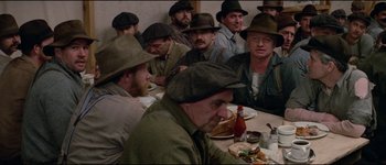 Movie still from “The Journey of Natty Gann” (1985), directed by Jeremy Kagan – A group of men sitting at a table eating food; Medium shot, High angle