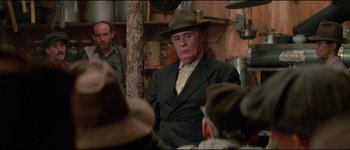 Movie still from “The Journey of Natty Gann” (1985), directed by Jeremy Kagan – An older man wearing a hat in a room; Medium shot, Over the shoulder angle