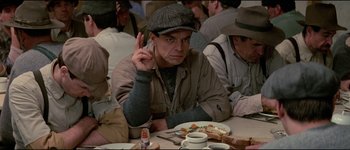Movie still from “The Journey of Natty Gann” (1985), directed by Jeremy Kagan – A man sitting at a table in front of a plate of food; Close Up shot, Over the shoulder angle