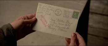 Movie still from “The Journey of Natty Gann” (1985), directed by Jeremy Kagan – A person holding an envelope that says return sender; Extreme Close Up shot, Overhead angle