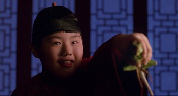 Movie still from “The Joy Luck Club” (1993), directed by Wayne Wang – A young boy wearing a black hat is holding a piece of food in his hand; Close Up shot, Low angle