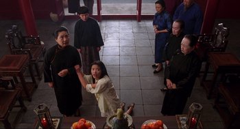 Movie still from “The Joy Luck Club” (1993), directed by Wayne Wang – A group of people standing around a table with food; Medium shot, High angle