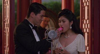 Movie still from “The Joy Luck Club” (1993), directed by Wayne Wang – A man and a woman in formal wear eating a donut; Medium shot, Over the shoulder angle