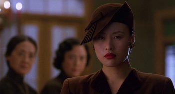 Movie still from “The Joy Luck Club” (1993), directed by Wayne Wang – A woman wearing a brown hat and a brown suit; Close Up shot, Over the shoulder angle