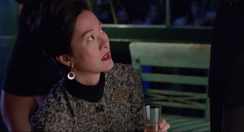 Movie still from “The Joy Luck Club” (1993), directed by Wayne Wang – A woman sitting at a table holding a glass of wine; Close Up shot, Over the shoulder angle