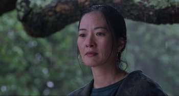 Movie still from “The Joy Luck Club” (1993), directed by Wayne Wang – A person wearing a jacket near a tree; Close Up shot, Low angle