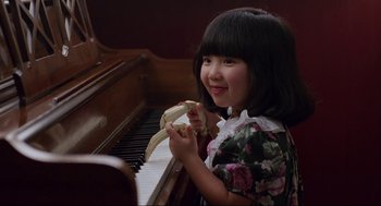 Movie still from “The Joy Luck Club” (1993), directed by Wayne Wang – A little girl sitting at a piano with a banana in her hand; Close Up shot, High angle