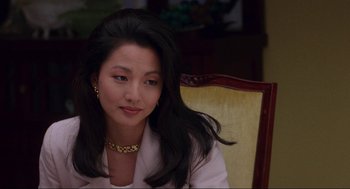 Movie still from “The Joy Luck Club” (1993), directed by Wayne Wang – A woman sitting in a chair wearing a gold necklace; Close Up shot, Over the shoulder angle