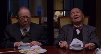 Movie still from “The Joy Luck Club” (1993), directed by Wayne Wang – Two older men sitting at a table with plates of food in front of them; Medium shot, Low angle