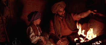 Movie still from “The Jungle Book” (1994), directed by Stephen Sommers – A man and a child sitting next to each other; Medium shot, Over the shoulder angle
