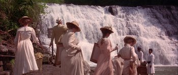 Movie still from “The Jungle Book” (1994), directed by Stephen Sommers – A group of people standing next to each other near a waterfall; Wide shot, High angle