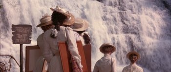 Movie still from “The Jungle Book” (1994), directed by Stephen Sommers – Two women and a boy are standing near a waterfall; Wide shot, High angle