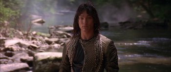 Movie still from “The Jungle Book” (1994), directed by Stephen Sommers – A man with long black hair wearing a black shirt; Close Up shot, Low angle