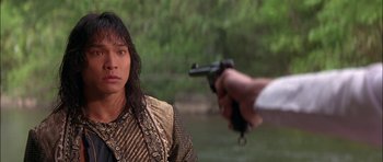 Movie still from “The Jungle Book” (1994), directed by Stephen Sommers – A man holding a gun in front of a woman in front of a body of water; Close Up shot, Over the shoulder angle