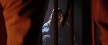 Movie still from “The Jungle Book” (1994), directed by Stephen Sommers – A person sitting in a dark room with a light shining on them; Close Up shot, Low angle