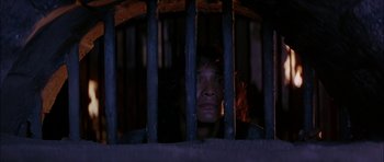 Movie still from “The Jungle Book” (1994), directed by Stephen Sommers – A woman looking through the bars of a jail cell; Close Up shot, Low angle