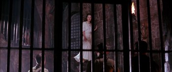 Movie still from “The Jungle Book” (1994), directed by Stephen Sommers – A woman in a white dress standing in front of a stone wall; Wide shot, High angle
