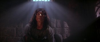 Movie still from “The Jungle Book” (1994), directed by Stephen Sommers – A man sitting in a chair in a dark room; Medium shot, Low angle