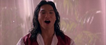 Movie still from “The Jungle Book” (1994), directed by Stephen Sommers – A man with long black hair is singing; Close Up shot, Low angle