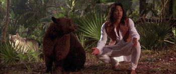 Movie still from “The Jungle Book” (1994), directed by Stephen Sommers – A man kneeling down next to a bear in the woods; Medium shot, Low angle