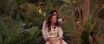 Movie still from “The Jungle Book” (1994), directed by Stephen Sommers – A man and a woman sitting on a bench in a forest; Medium shot, High angle