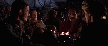 Movie still from “The Jungle Book” (1994), directed by Stephen Sommers – Two men sitting at a table with candles in front of them; Medium shot, Low angle