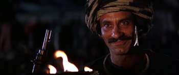 Movie still from “The Jungle Book” (1994), directed by Stephen Sommers – A person wearing a turban with fire in the background; Close Up shot, Low angle