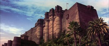 Movie still from “The Jungle Book” (1994), directed by Stephen Sommers – A castle like building with a palm tree in front of it; Extreme Wide shot, Low angle