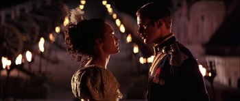 Movie still from “The Jungle Book” (1994), directed by Stephen Sommers – A man and a woman standing next to each other in front of lights; Medium shot, Low angle