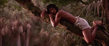Movie still from “The Jungle Book” (1994), directed by Stephen Sommers – A man laying on top of a tree branch; Wide shot, Low angle