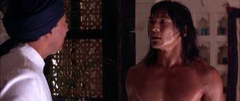 Movie still from “The Jungle Book” (1994), directed by Stephen Sommers – A man with long black hair is looking at the camera; Close Up shot, Over the shoulder angle