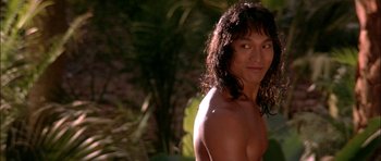 Movie still from “The Jungle Book” (1994), directed by Stephen Sommers – A man with long hair and a bare - chested face; Close Up shot, Over the shoulder angle