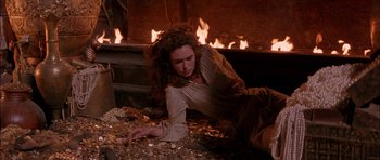 Movie still from “The Jungle Book” (1994), directed by Stephen Sommers – A woman laying on the ground in front of a fire; Medium shot, High angle