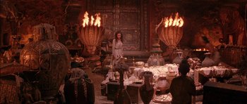 Movie still from “The Jungle Book” (1994), directed by Stephen Sommers – A woman standing in front of a room filled with furniture; Wide shot, High angle