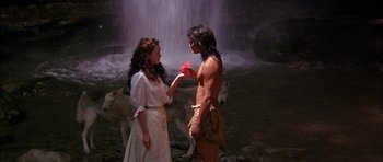 Movie still from “The Jungle Book” (1994), directed by Stephen Sommers – A man and a woman holding hands in front of a waterfall; Medium shot, High angle