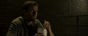 Movie still from “Department Q: The Keeper of Lost Causes” (2013), directed by Mikkel Nørgaard – A man sitting at a table holding a piece of paper; Close Up shot, Low angle