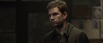 Movie still from “Department Q: The Keeper of Lost Causes” (2013), directed by Mikkel Nørgaard – A person wearing a suit and tie; Close Up shot, Over the shoulder angle