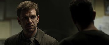 Movie still from “Department Q: The Keeper of Lost Causes” (2013), directed by Mikkel Nørgaard – A man in a brown jacket talking to another man in a brown jacket; Close Up shot, Over the shoulder angle