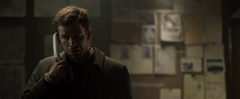 Movie still from “Department Q: The Keeper of Lost Causes” (2013), directed by Mikkel Nørgaard – A man standing in a dark room looking down at the floor; Close Up shot, Over the shoulder angle