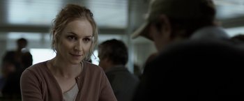 Movie still from “Department Q: The Keeper of Lost Causes” (2013), directed by Mikkel Nørgaard – A woman is looking at the camera while a man stands in the background; Close Up shot, Over the shoulder angle