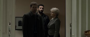 Movie still from “Department Q: The Keeper of Lost Causes” (2013), directed by Mikkel Nørgaard – A woman standing next to two men in a room; Medium shot, Over the shoulder angle