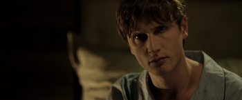 Movie still from “Department Q: The Keeper of Lost Causes” (2013), directed by Mikkel Nørgaard – A young man with a creepy look on his face; Close Up shot, Over the shoulder angle