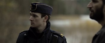 Movie still from “Department Q: The Keeper of Lost Causes” (2013), directed by Mikkel Nørgaard – A man in a military uniform with a hat on; Close Up shot, Over the shoulder angle