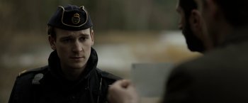 Movie still from “Department Q: The Keeper of Lost Causes” (2013), directed by Mikkel Nørgaard – A man in a uniform is holding a piece of paper; Close Up shot, Over the shoulder angle