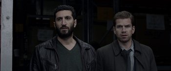 Movie still from “Department Q: The Keeper of Lost Causes” (2013), directed by Mikkel Nørgaard – Two men standing next to each other wearing jackets; Medium shot, Over the shoulder angle